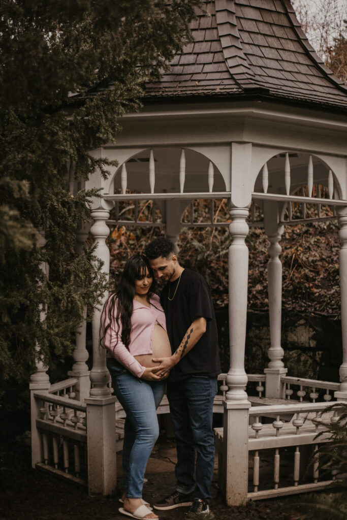 Husband and wife in gazebo having a maternity photoshoot.