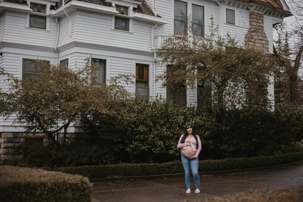 Expecting mother standing in front of the historic Victorian-era Deepwood Museum.